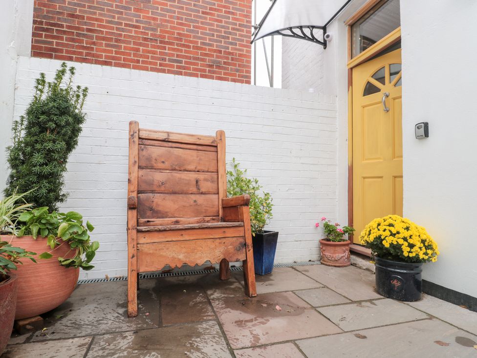 An outdoor area with a wooden chair and potted plants at Bohemian Beach Cottage in Bournemouth