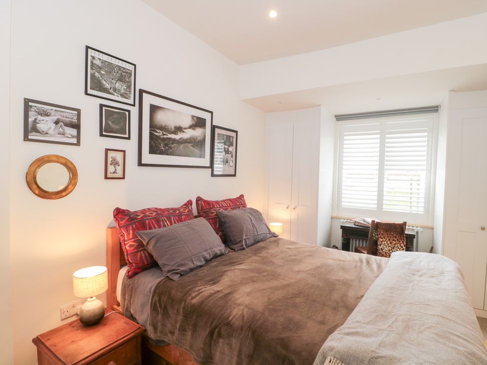 A bedroom with a bed, bedside lamp, and photographs at Bohemian Beach Cottage in Bournemouth