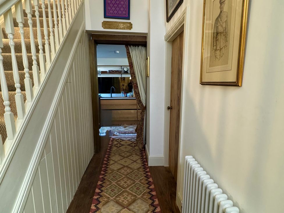 A hallway with a staircase and curtain leading to the kitchen at Bohemian Beach Cottage in Bournemouth