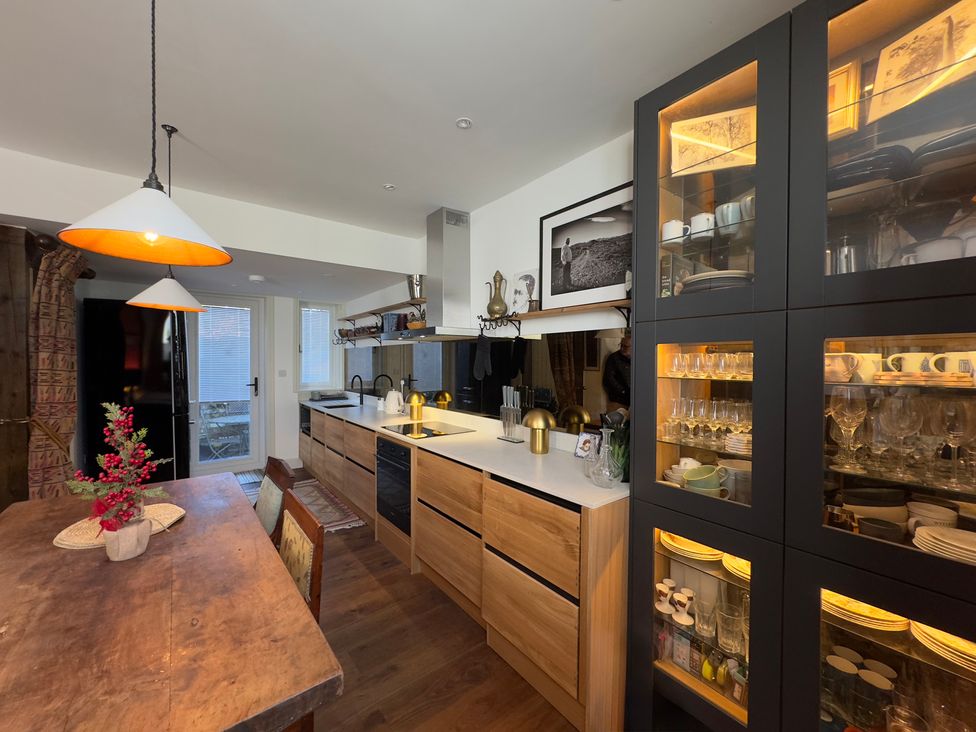 A kitchen with cabinets and a dining table at Bohemian Beach Cottage in Bournemouth