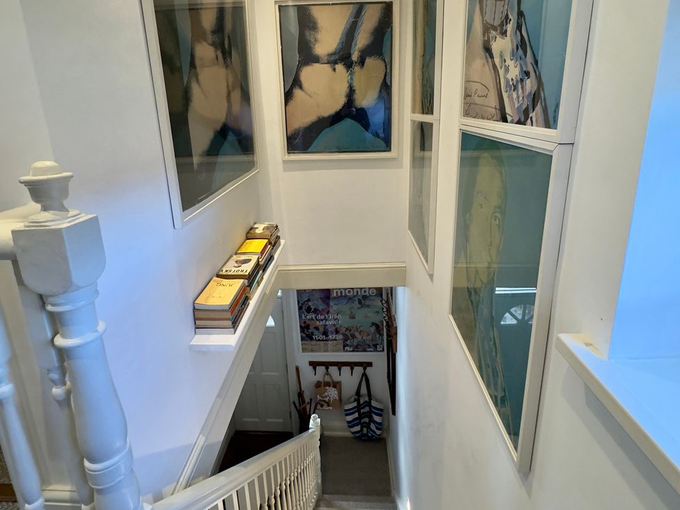 A staircase with paintings and books at Bohemian Beach Cottage in Bournemouth