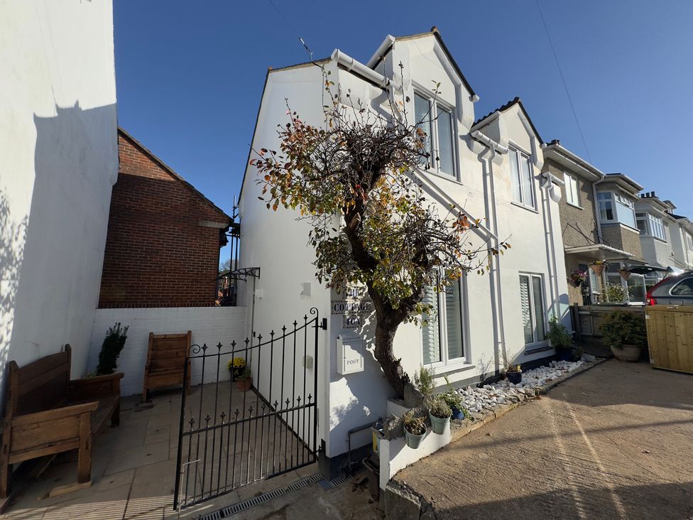 An outdoor view of a house with a tree and gated entrance at Bohemian Beach Cottage in Bournemouth