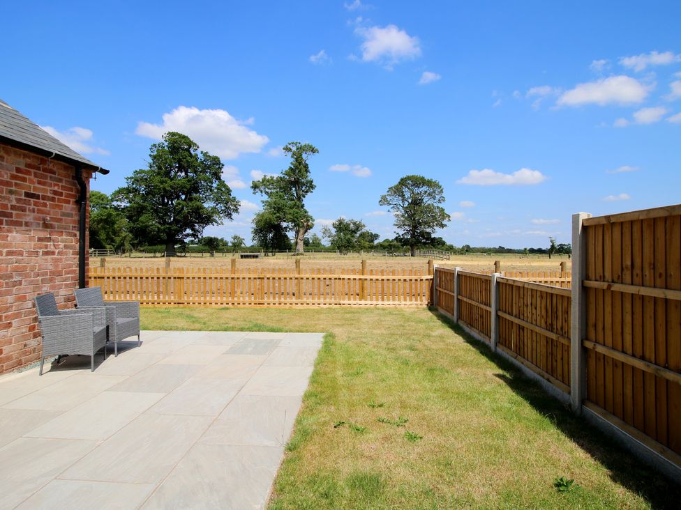 A garden with patio chairs and a fenced area at Chestnut Barn in Shrewsbury