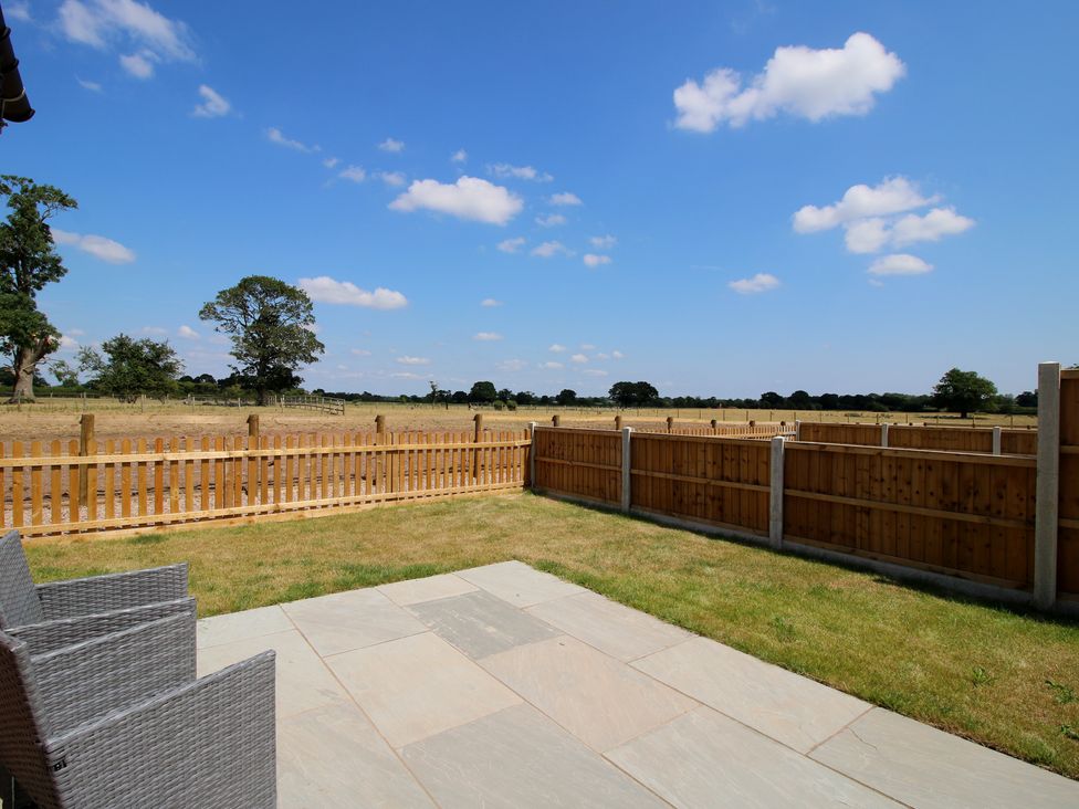 An outdoor patio area with grass and a fence at Chestnut Barn in Shrewsbury