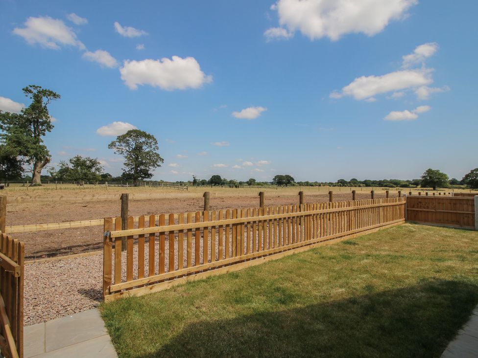 A garden with a fenced area and trees at Chestnut Barn in Shrewsbury