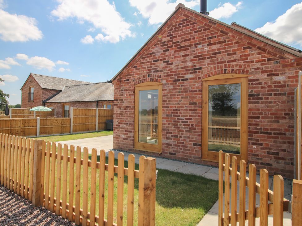 A garden area with a brick structure and a fenced patio at Chestnut Barn in Shrewsbury