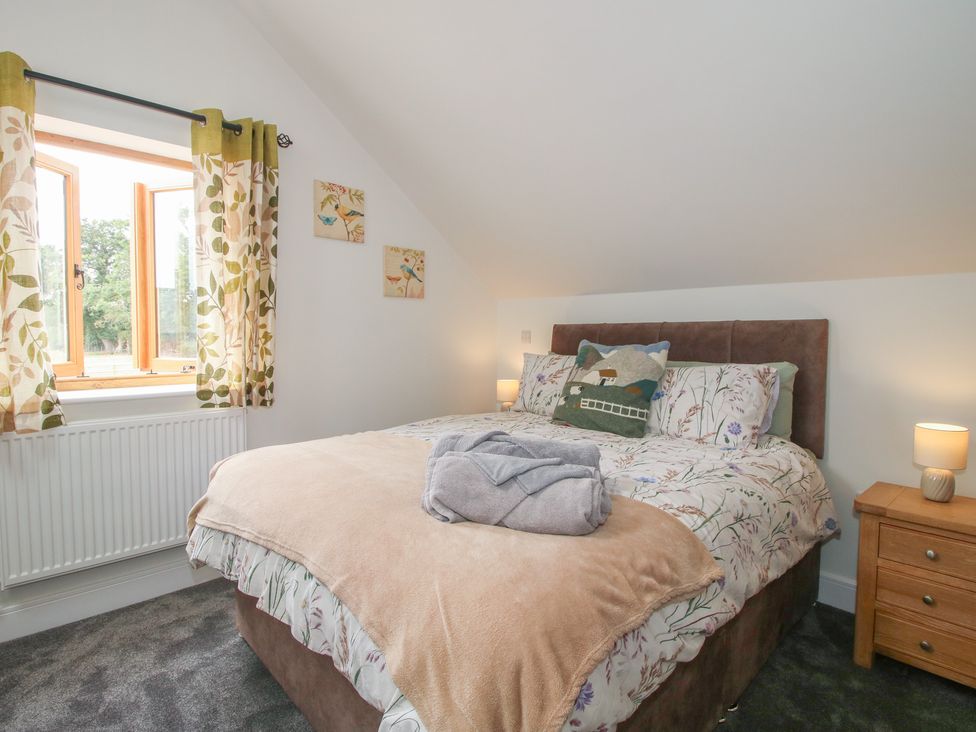 A bedroom with a bed and windows at Chestnut Barn in Northwood near Wem
