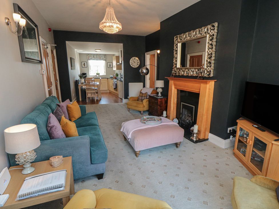 A living room with a sofa, armchair, coffee table, and a fireplace at Stanton House - Abbey View, Flat 3 