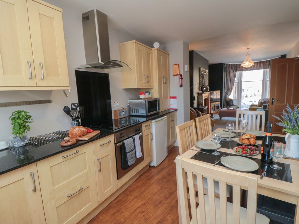 A kitchen with cabinets and dining table at Stanton House - Abbey View, Flat 3