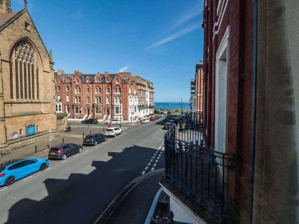 A view of a street with buildings and cars, with the ocean in the distance at Stanton House - Abbey View, Flat 3