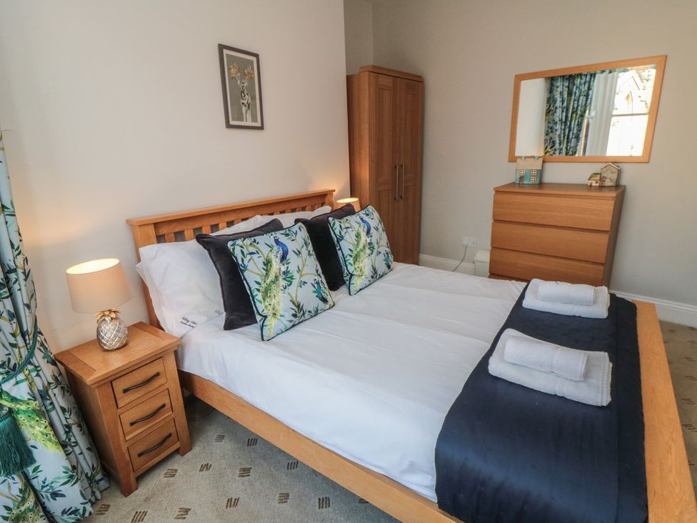 A bedroom with a bed, bedside table, lamp, and dresser at Stanton House - Abbey View, Flat 3