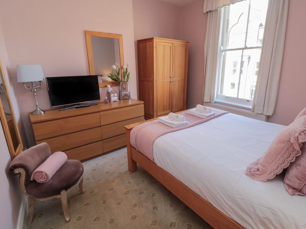 A bedroom with a bed, dresser, and television at Stanton House - Abbey View, Flat 3