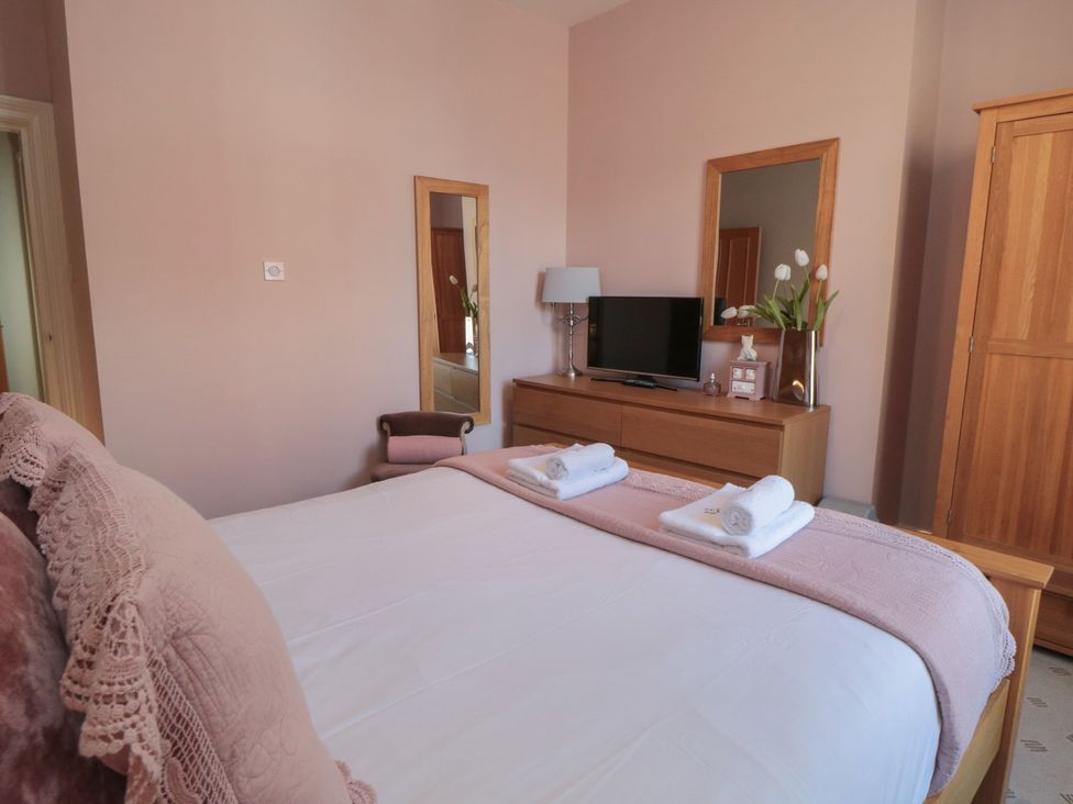 A bedroom with a bed, television and flowers at Stanton House - Abbey View, Flat 3