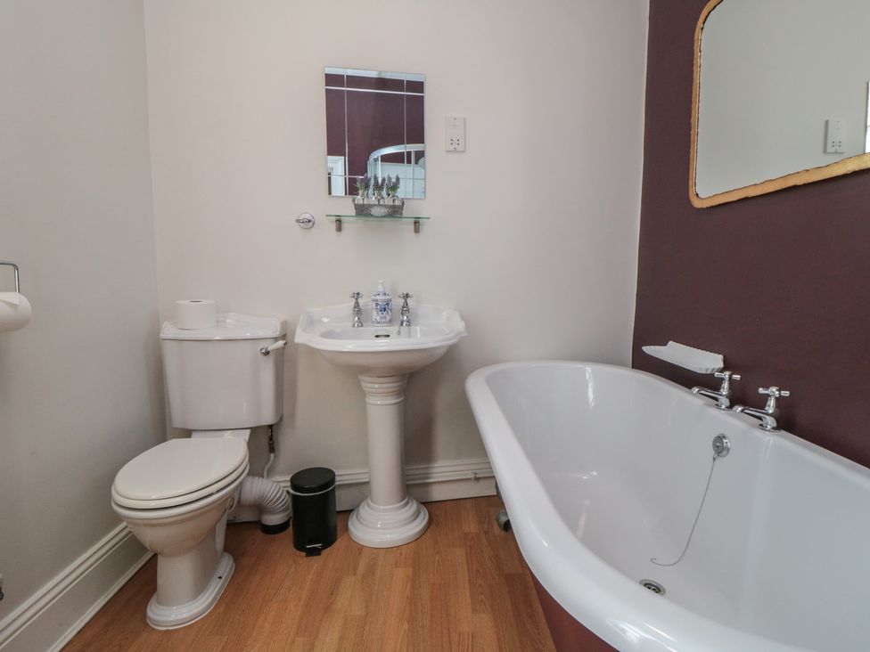 A bathroom with a bathtub, sink, toilet, and mirror at Stanton House - Abbey View, Flat 3