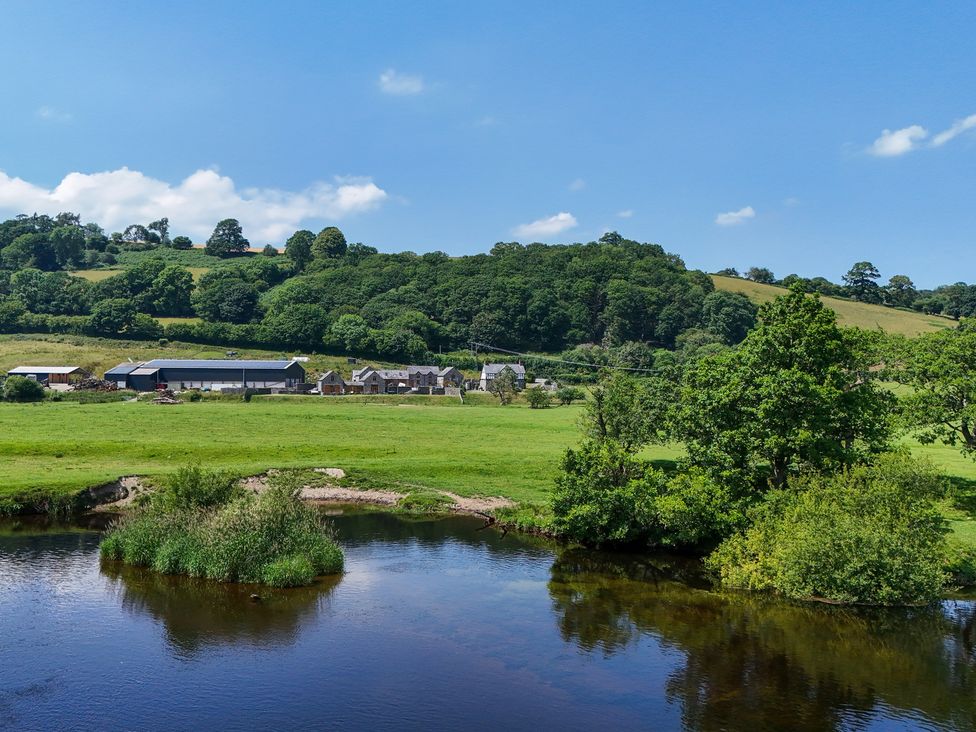 A rural landscape with buildings and a river at The Dairy in Corwen