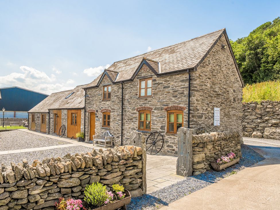 A stone house with a garden area and gravel path at The Dairy in Corwen