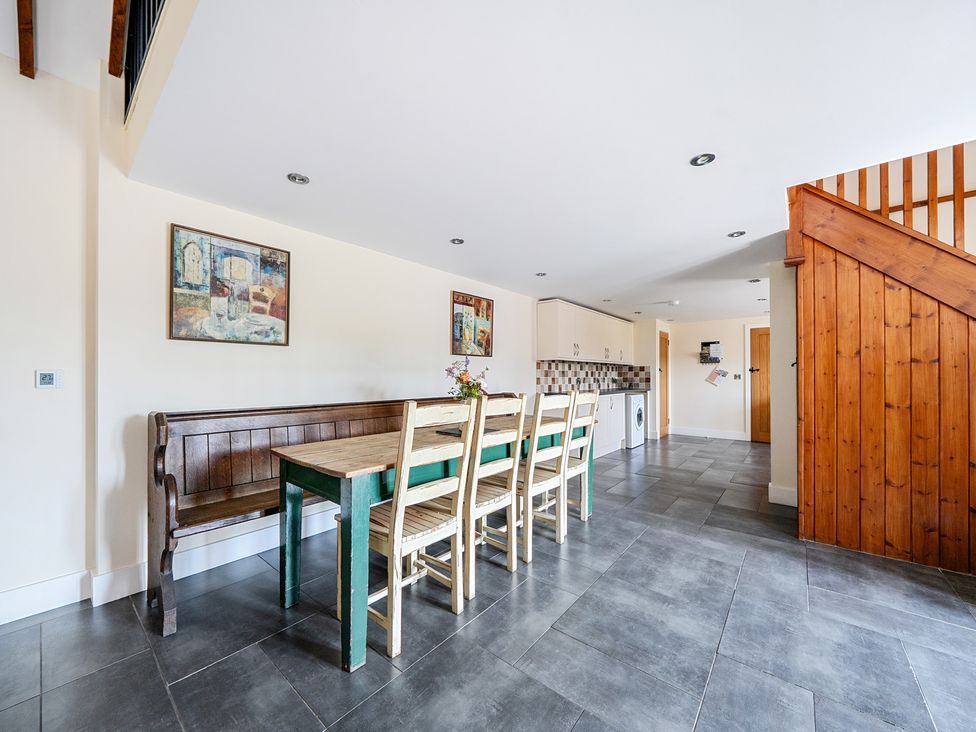 A dining room with a table and benches at The Dairy in Corwen