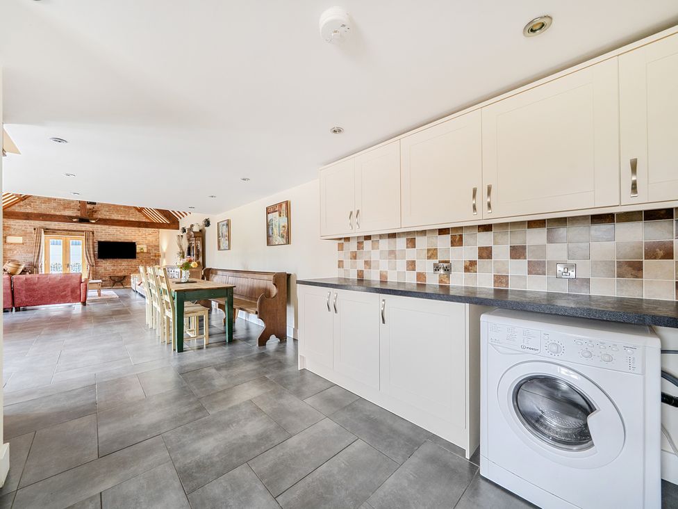 A kitchen with a washing machine and table at The Dairy in Corwen