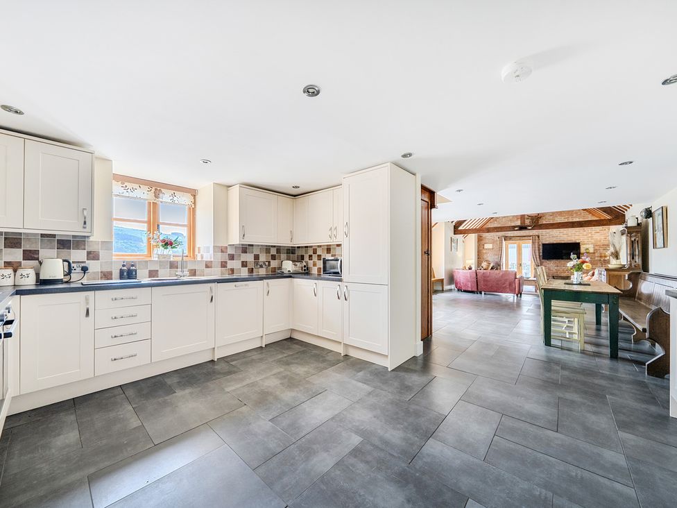 A kitchen with cabinets and a dining table at The Dairy in Corwen