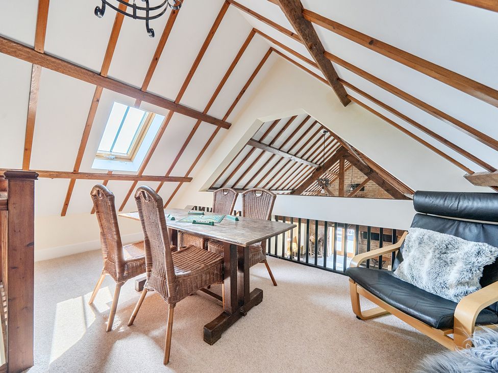 A loft with a dining table and chairs at The Dairy in Corwen