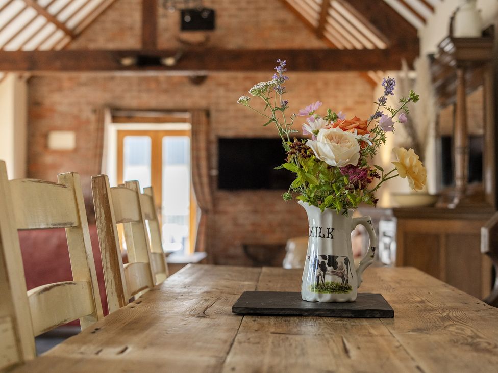A dining room with a table and chairs and a vase of flowers at The Dairy in Corwen