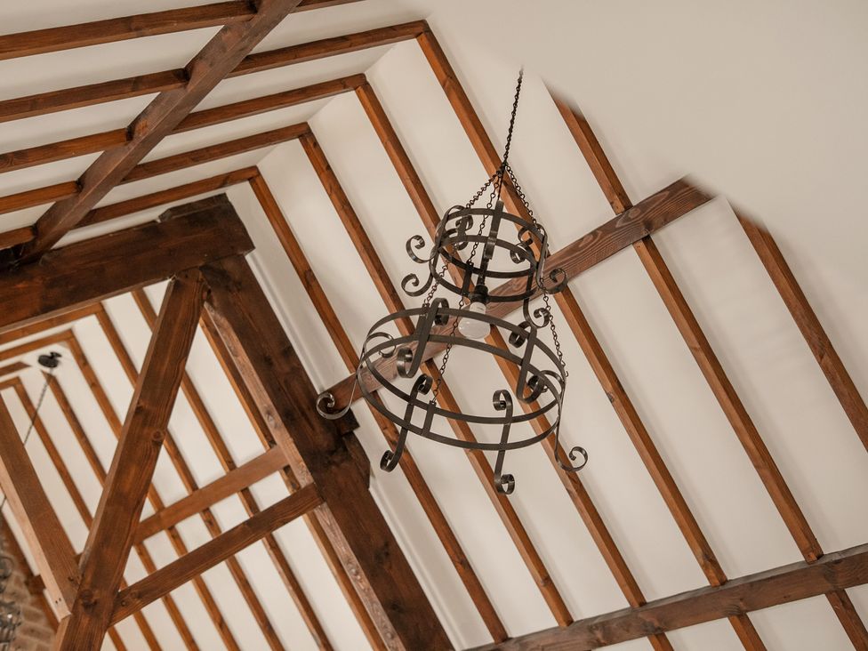 A chandelier hanging from the ceiling with wood beams at The Dairy in Corwen
