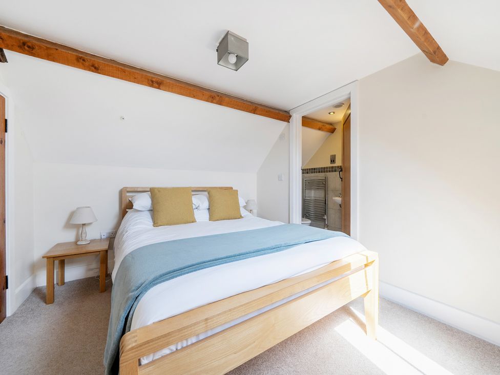 A bedroom with a bed and attached bathroom at The Dairy Corwen