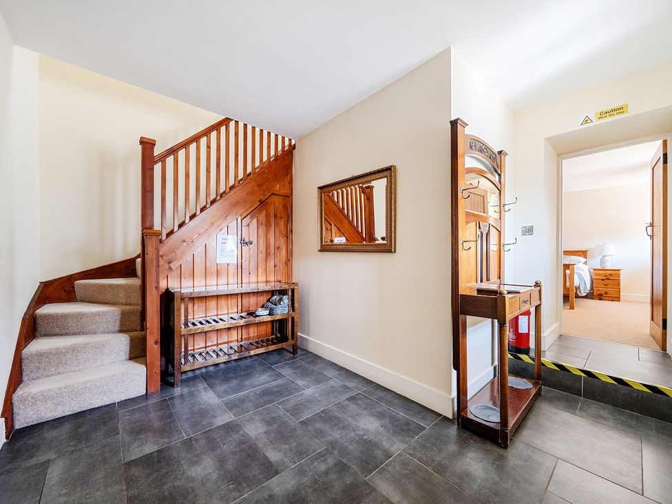A hallway with a staircase and coat rack at The Dairy in Corwen