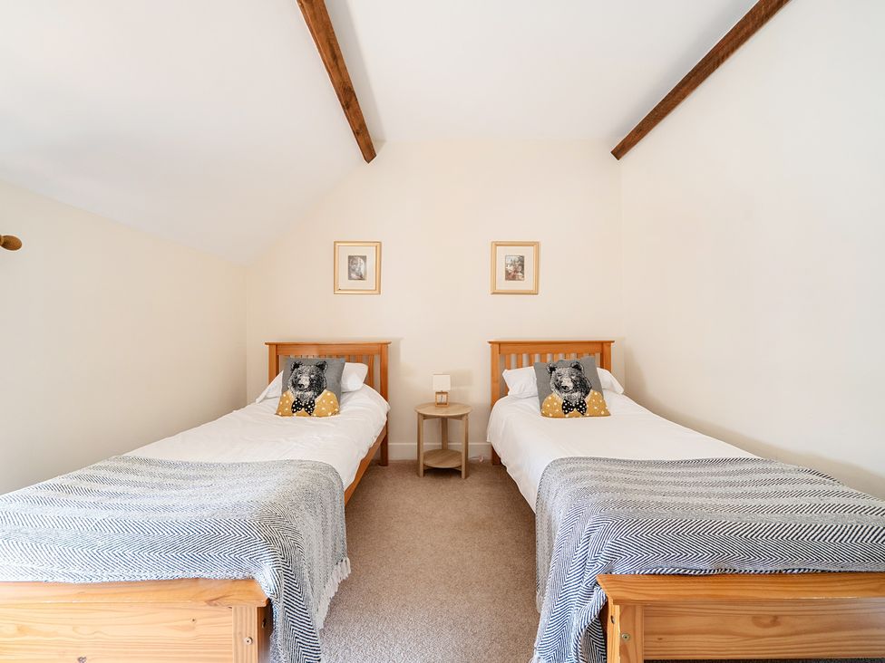 A bedroom with two beds and a nightstand at The Dairy in Corwen