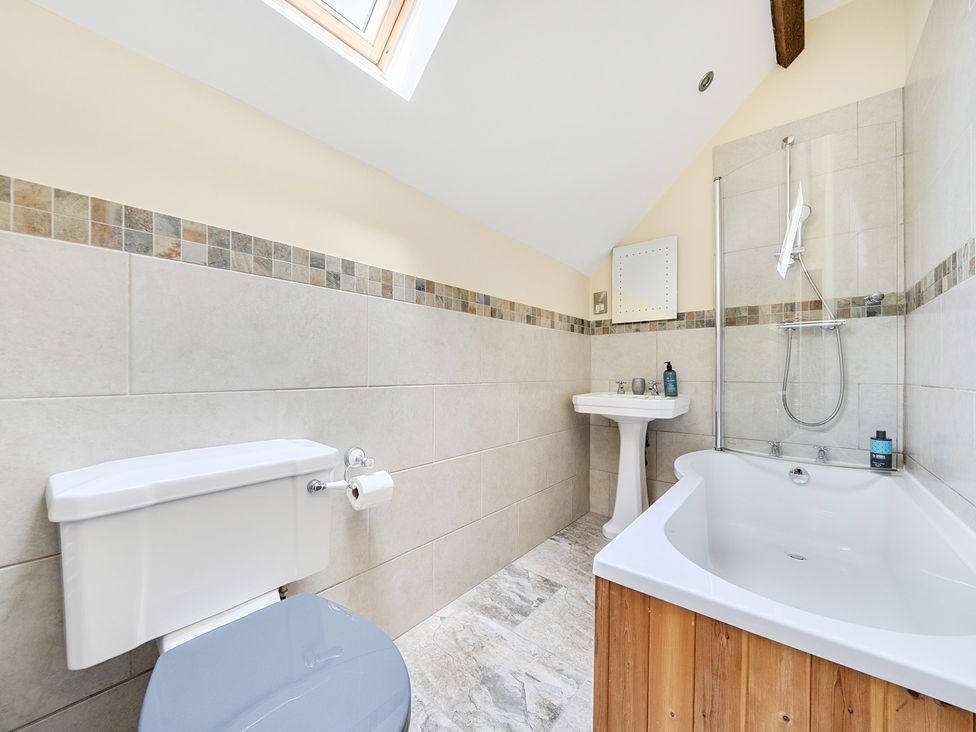 A bathroom with a sink, shower, bath, and a toilet at The Dairy in Corwen