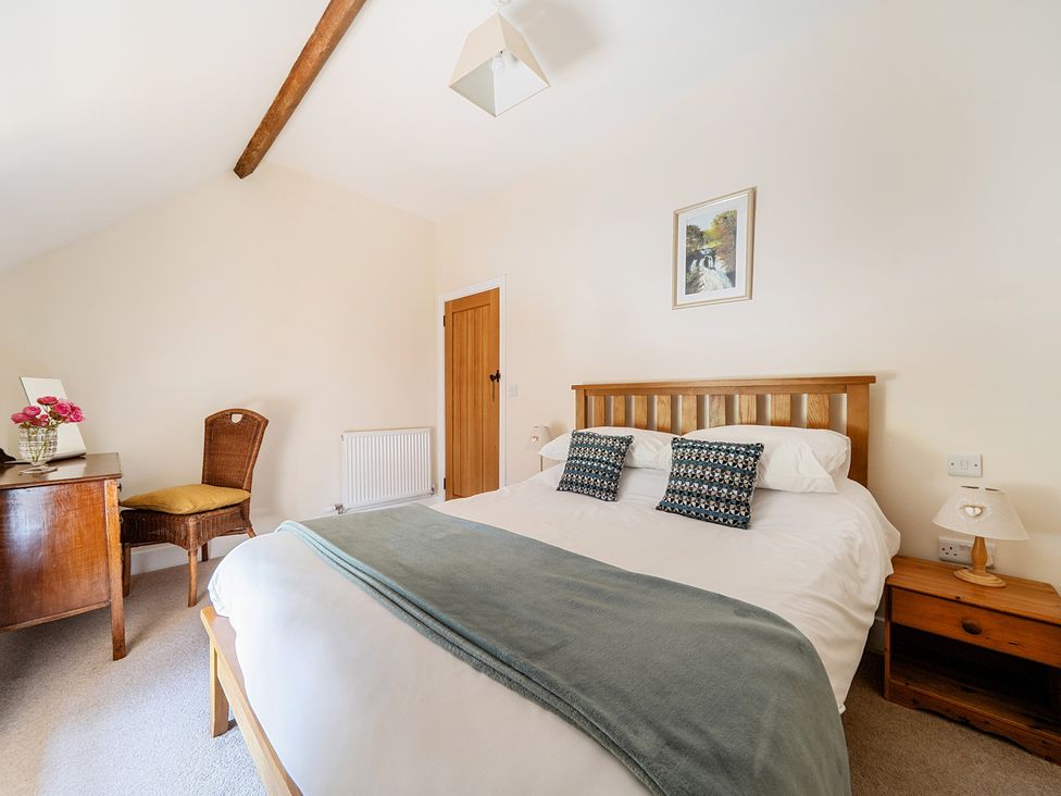A bedroom with a bed, desk, and chair at The Dairy in Corwen