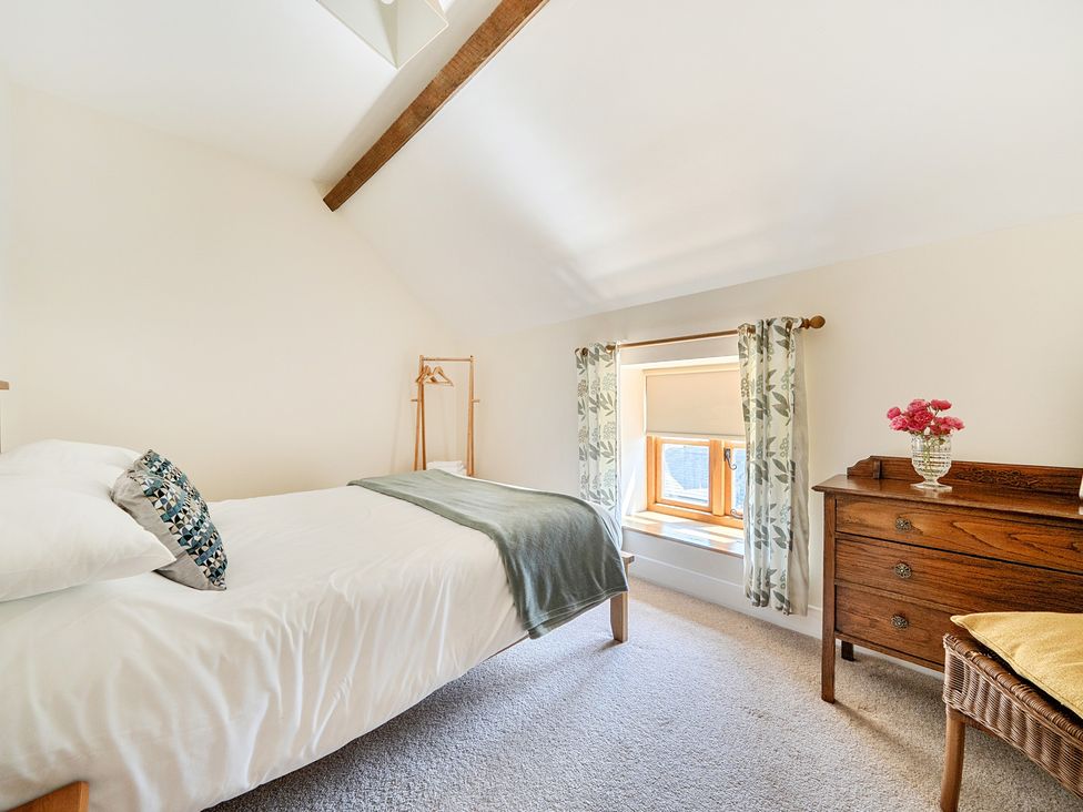A bedroom with a bed and a window at The Dairy in Corwen