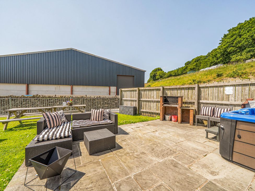 An outdoor area with a sofa and hot tub at The Dairy in Corwen