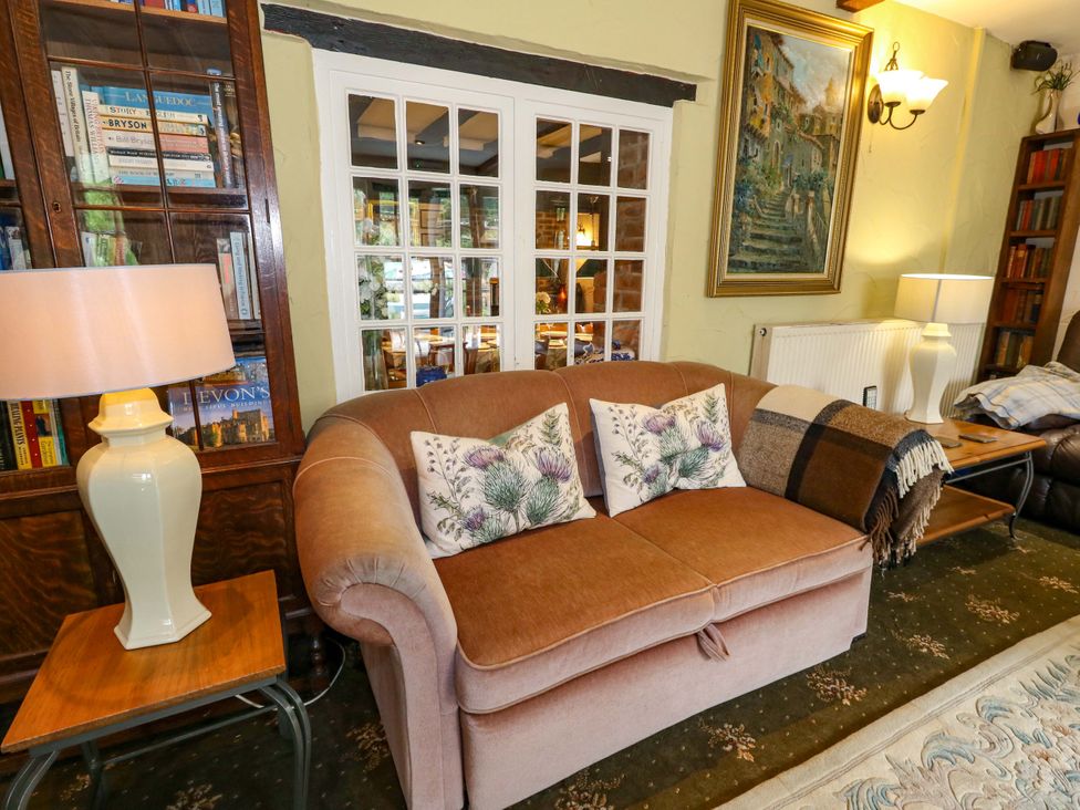 A living room with a sofa and bookshelf at Piddle Inn in Piddletrenthide