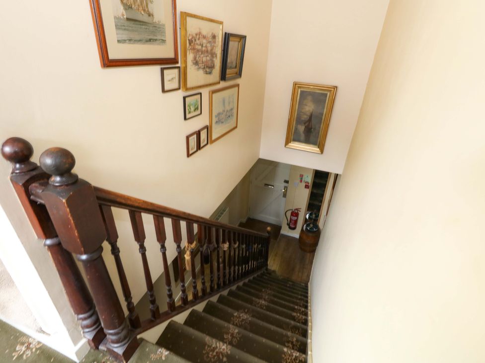 A staircase leading down with paintings on the wall at Piddle Inn in Piddletrenthide