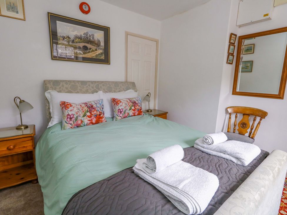 A bedroom with a bed, lamp, and mirror at Piddle Inn in Piddletrenthide