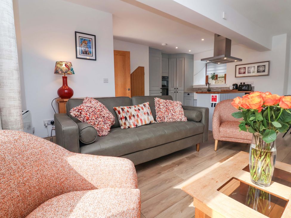A living room with a sofa, armchairs, and a kitchen area at Butterfly Days in Bideford