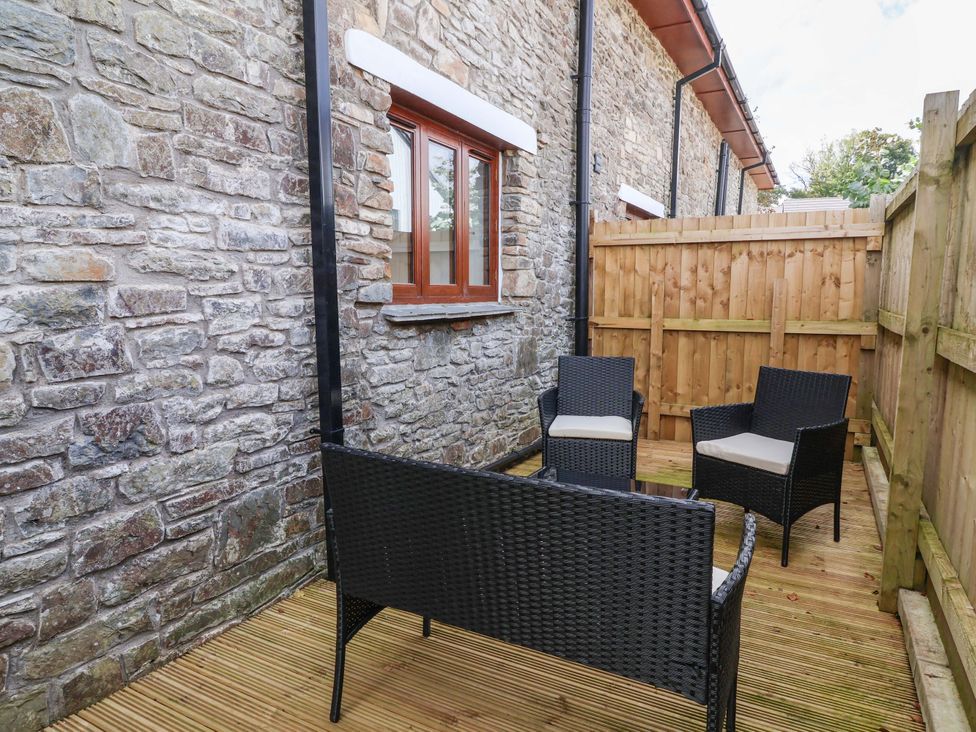 An outdoor seating area with chairs and a stone wall at Butterfly Days in Bideford