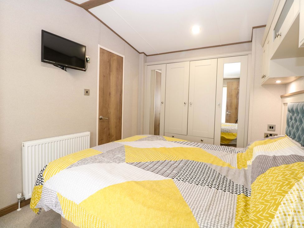 A bedroom with a bed, wardrobe, and television at 17 Castle Walk in Great Yarmouth