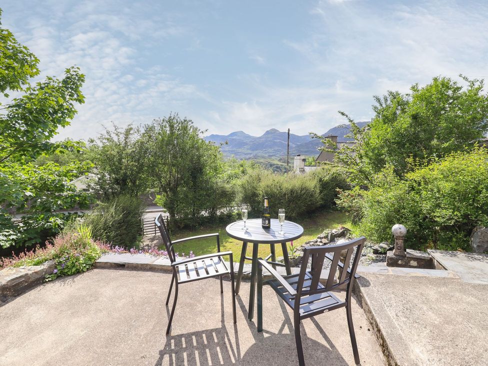 A table and chairs with a bottle and glasses in an outdoor area at Brondderwen