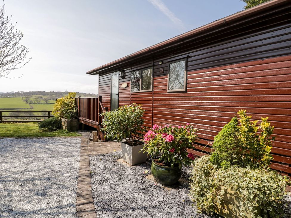 A wooden building with deck and flower pots at Summertime Lodge in Rhyd-y-Foel near Abergele