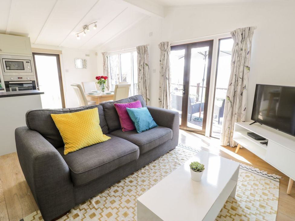 A living room with a sofa and a dining area at Summertime Lodge Rhyd-y-Foel near Abergele
