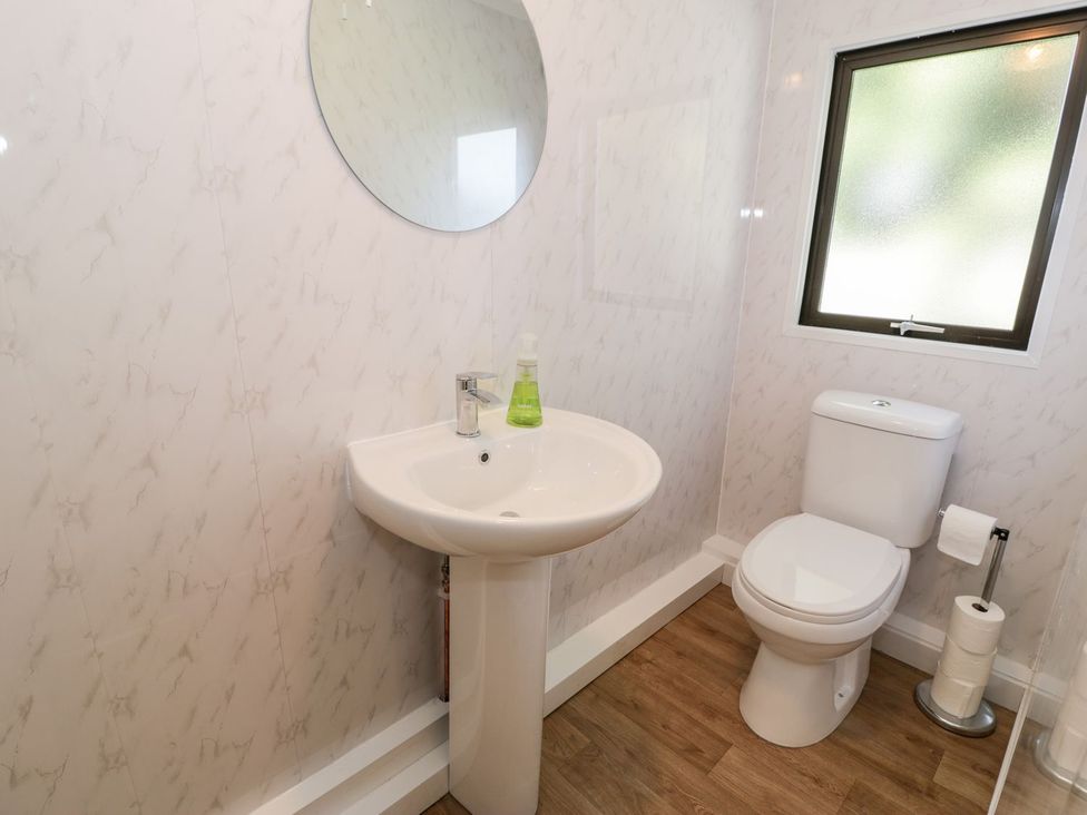 A bathroom with a sink, toilet and mirror at Summertime Lodge in Rhyd-y-Foel near Abergele