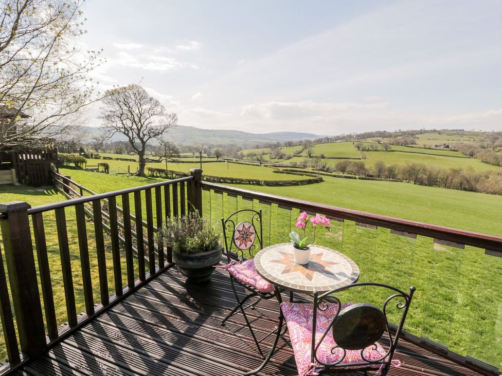 A deck with a table and chairs overlooking hills at Summertime Lodge in Rhyd-y-Foel near Abergele