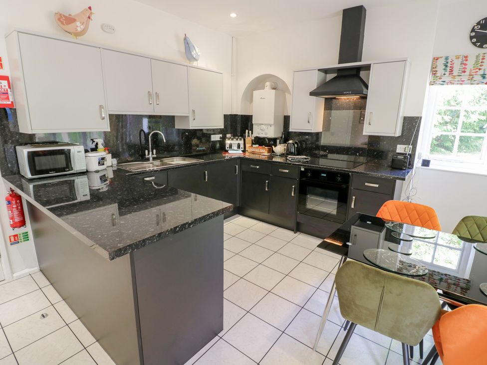 A kitchen with worktop, dining table, and appliances at Raglan Lodge in Monmouth