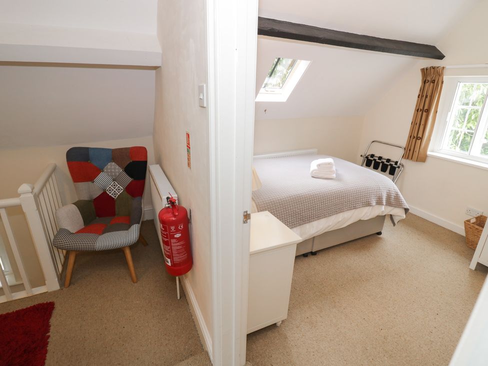 A bedroom with a bed and armchair at Hillside Cottage