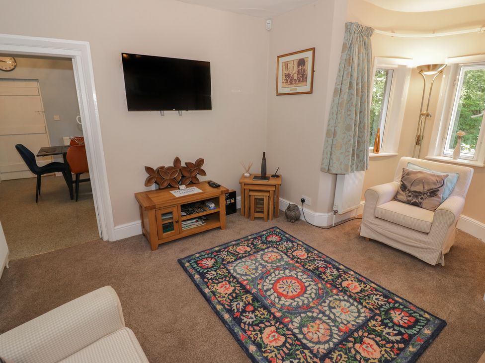A living room with a television and chair at Boxbush Lodge in Monmouth