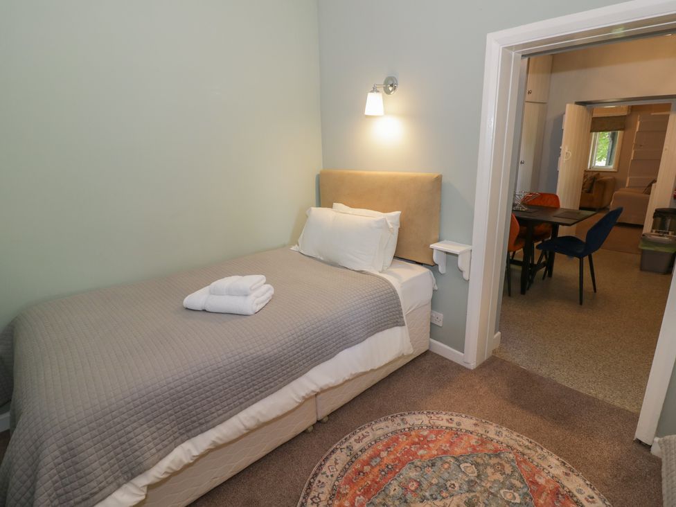 A bedroom with a single bed and an adjacent living area at Boxbush Lodge Monmouth