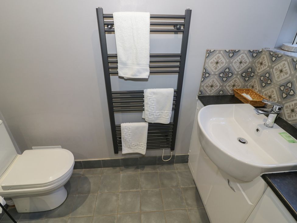 A bathroom with a toilet, towel rack, sink and wall decor at Boxbush Lodge in Monmouth