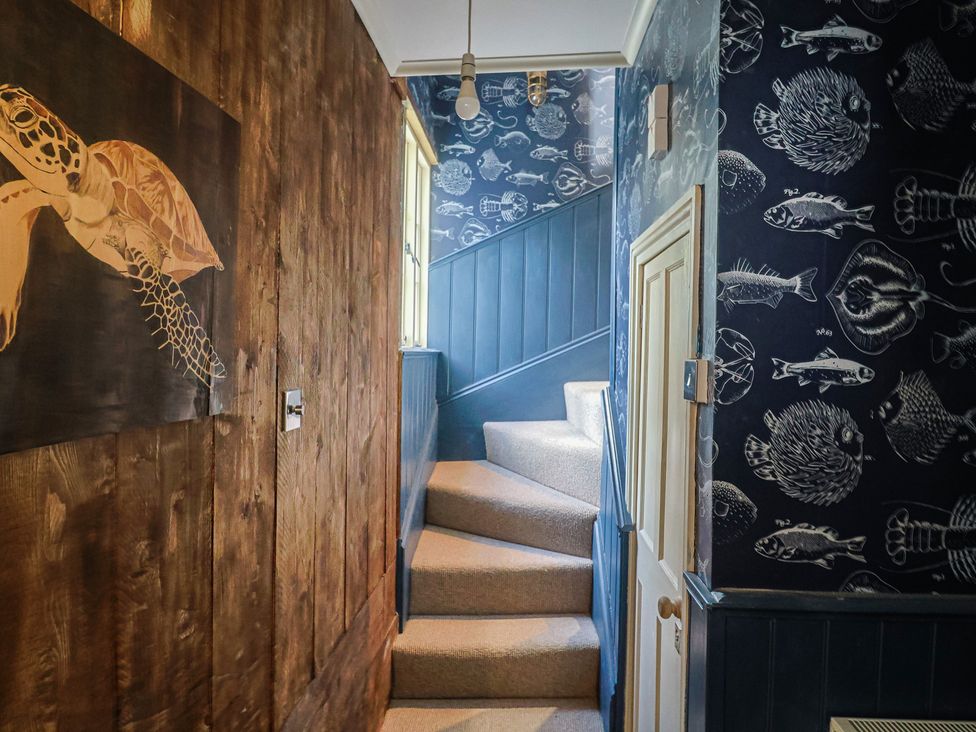 A stairway with a turtle painting and fish wallpaper at 5B Bridge Street in Lyme Regis